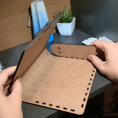 Manos armando un complemento en MDF tipo flexbox carpeta.
